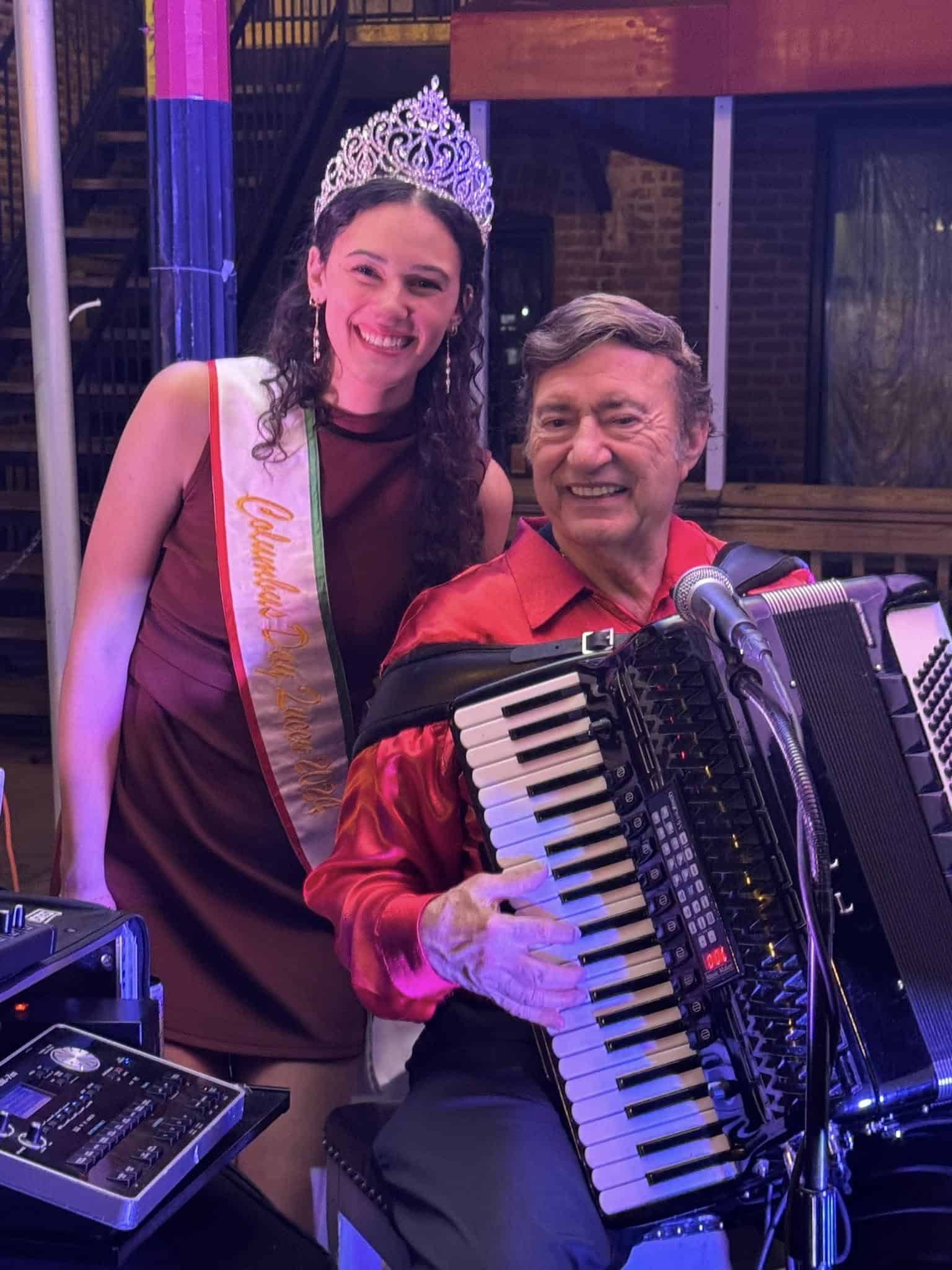 Joe Martino smiling with his accordion beside a guest at a celebration