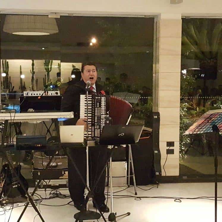 Joe Martino singing and playing accordion beside his keyboard